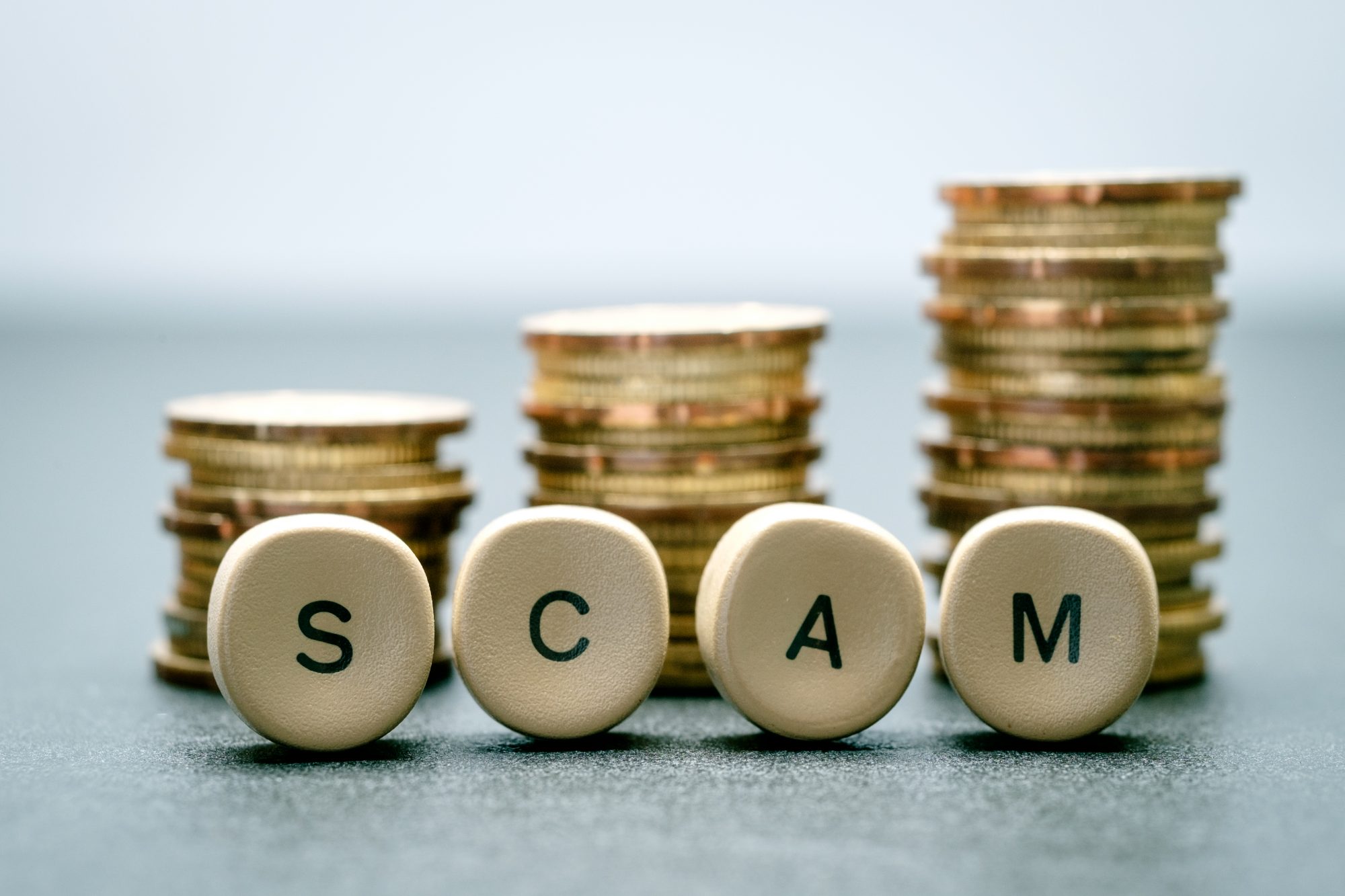 Scam scrabble letters in front of coins