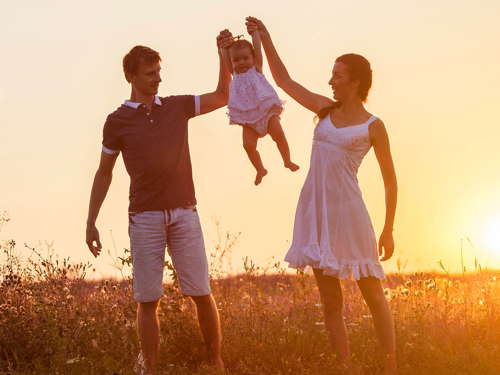 A kid being help up by their parents