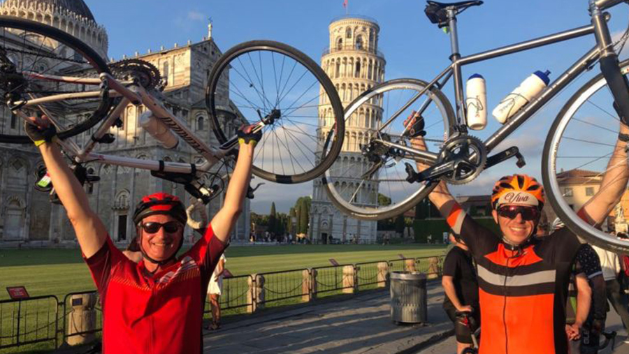 Two people holding their bikes above their heads