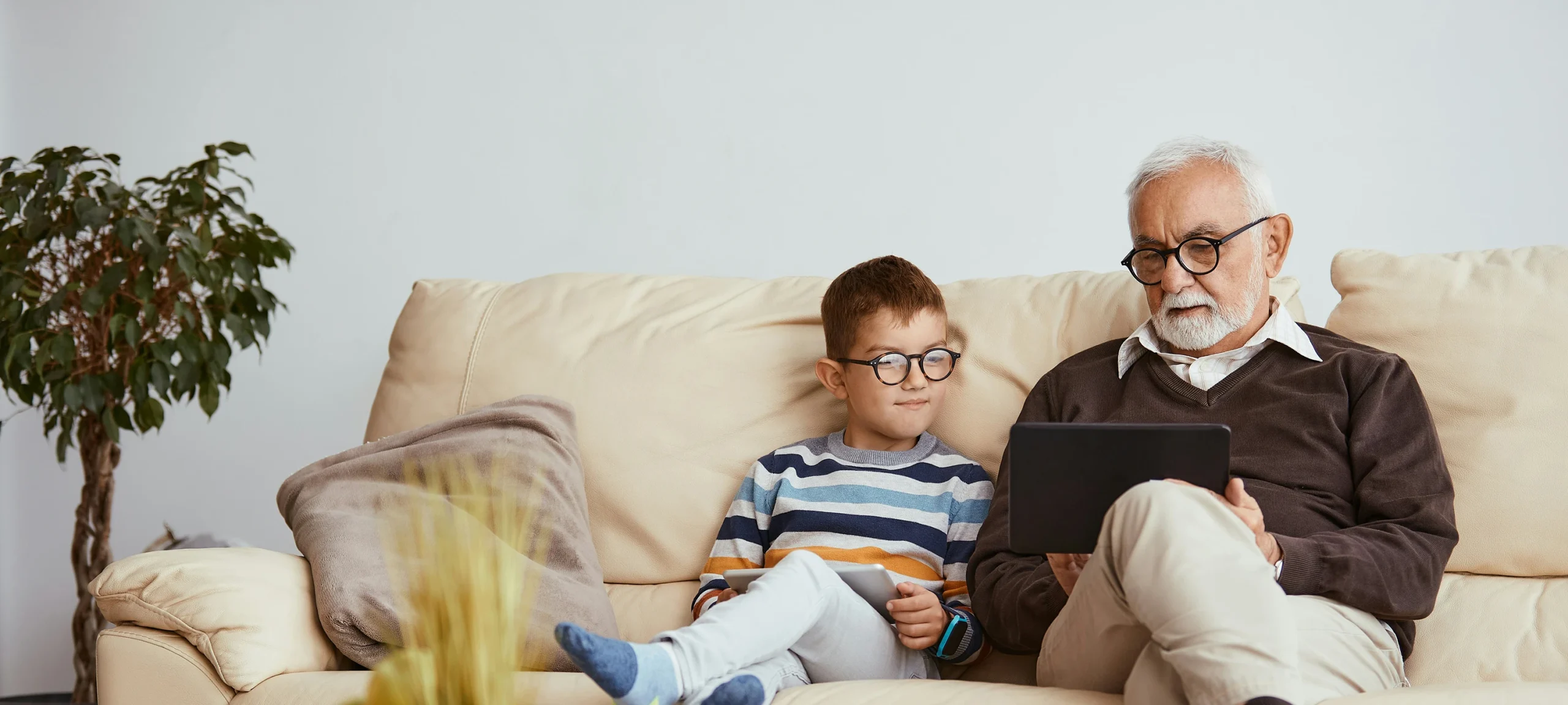 Young boy sitting next to grandad who has an iPad